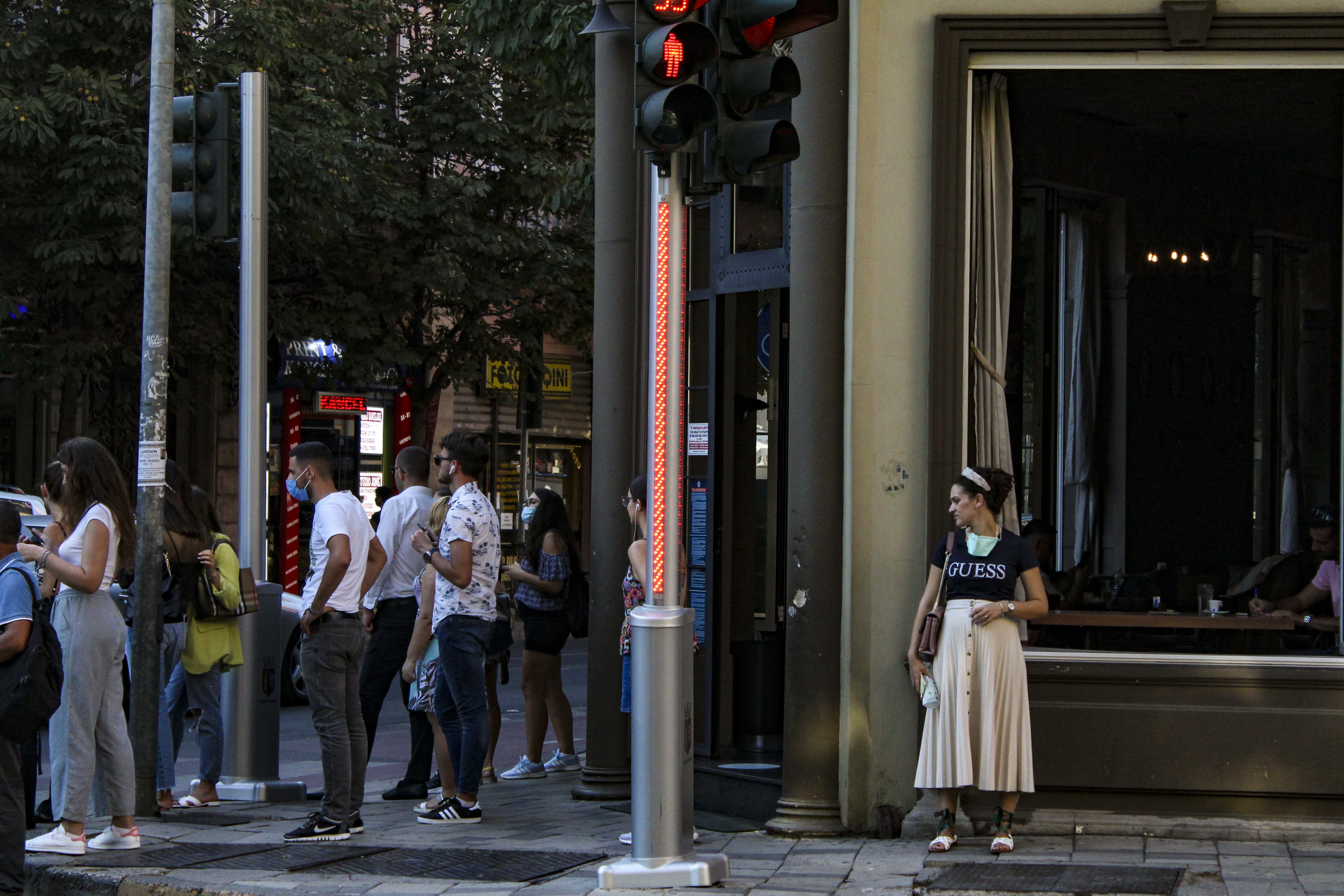 A pregnant woman avoids the crowd at an intersection crosswalk during the COVID-19 global pandemic in downtown Tirana, Albania on Thursday, Aug. 27, 2020. (Photo by Meng Wei)